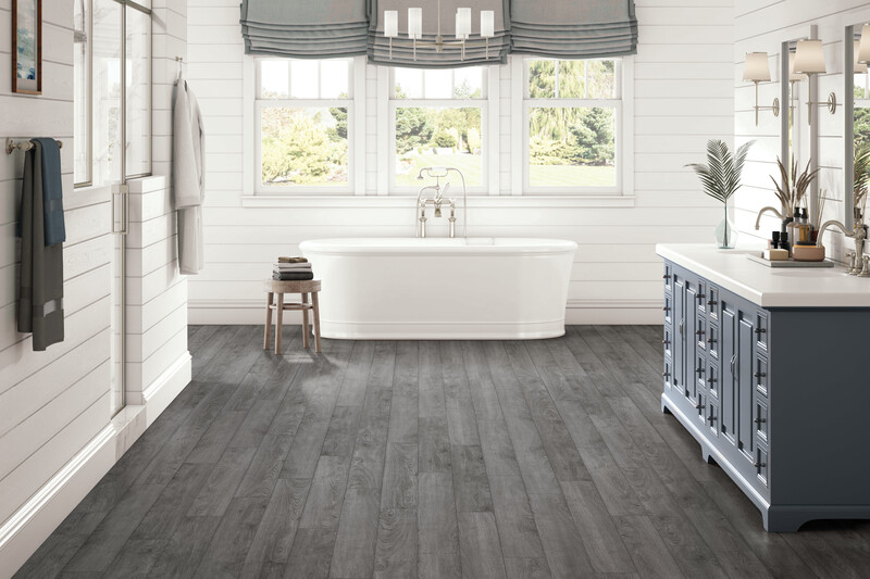 Bathroom with a tub underneath a picture window with wood-look vinyl fooring