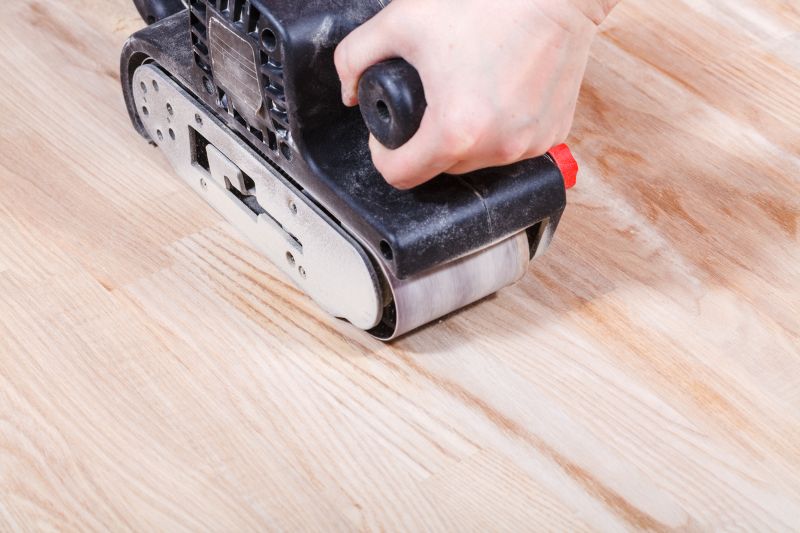 Close up of a man sanding a wood floor