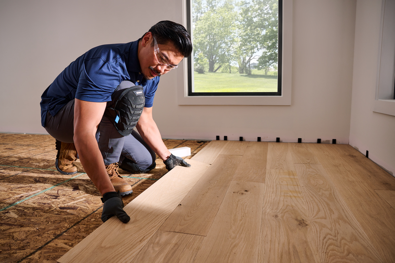 Man laying unfinished hardwood flooring planks