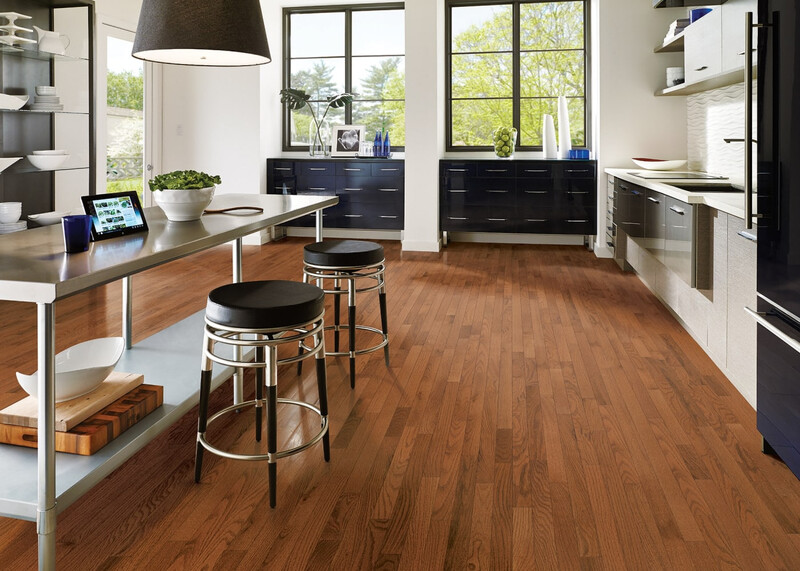 Hardwood flooring in kitchen with large windows and an island with stools